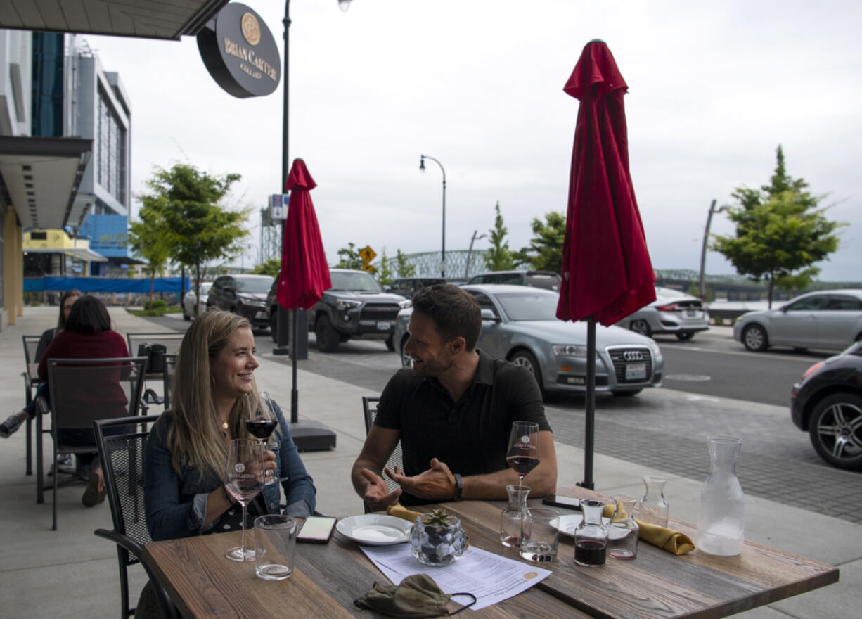 Seattle residents Becca Roundhill and Dominic Thibodeau enjoy red wine on an overcast April evening at Brian Carter Cellars at The Waterfront Vancouver. Getting a spot with a river view takes some planning.