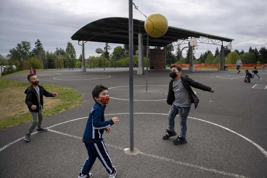 Kindergartners Makhari Lang, from left, Anthony Miller and Zephaniah Keli Aitu test their tetherball skills during recess at Eisenhower Elementary School on Monday. Vancouver Public Schools expanded in-person instruction for four grades and plans to expand to another four grades next week.