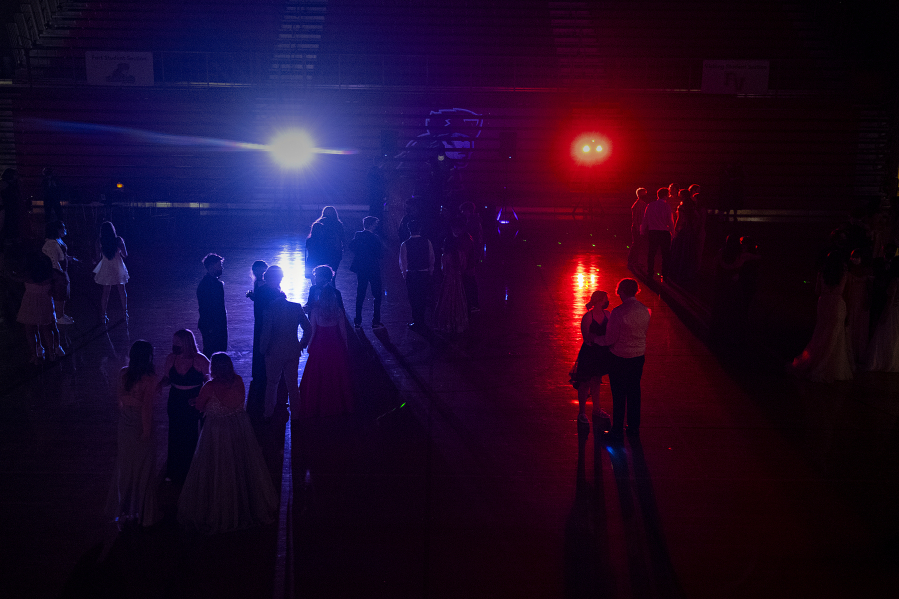 Colorful lights illuminate the gym at Fort Vancouver High School as students keep their distance while enjoying music, dancing and time with friends at the 2021 prom May 22. Some Clark County school districts did not permit traditional proms this spring for a second consecutive year because of COVID-19 safety restrictions. Others forged ahead this spring doing modified events or parent-driven pop-up proms not sponsored by schools.