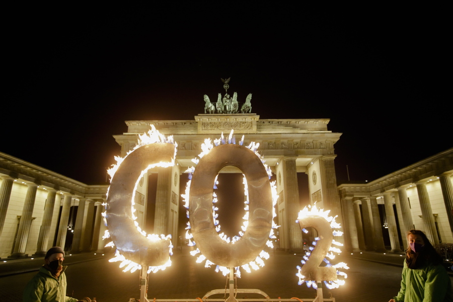Activists of the environment organization Greenpeace protest with CO2 letters illuminated with flames in front of the Brandenburg Gate against the climate change in Berlin, Germany, Thursday, May 6, 2021. The demonstrators demand German Chancellor Angela Merkel to push the fight against climate change during the 12th meeting of the Petersberg Climate Dialogue conference which take place on May 6 and 7, 2021.
