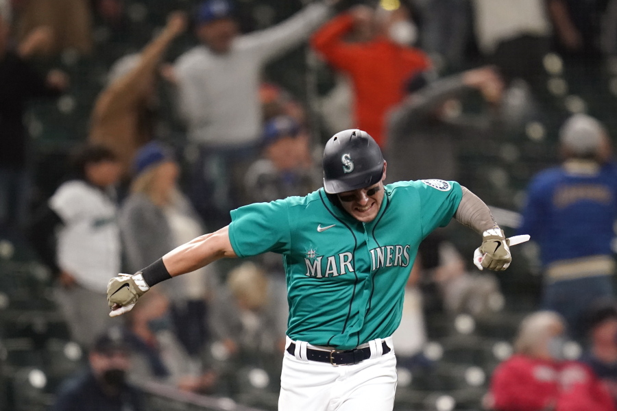 Seattle Mariners' Jarred Kelenic reacts to the home run of Mitch Haniger as he heads in to score against the Cleveland Indians during the seventh inning of a baseball game Friday, May 14, 2021, in Seattle.