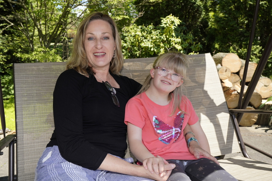 Holly Christensen, left, sits in a swing with her daughter, Lyra, Thursday, May 13, 2021, in Akron, Ohio. Anti-abortion activists say 2021 has been a breakthrough year for legislation in several states seeking to prohibit abortions based on a prenatal diagnosis of Down syndrome. Opponents of the bills, including some parents with children who have Down syndrome like Holly, argue that elected officials should not be meddling with a woman's deeply personal decision on whether to carry a pregnancy to term after a Down syndrome diagnosis.