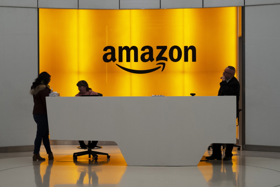 FILE - In this Feb. 14, 2019, file photo, people stand in the lobby for Amazon offices in New York. Amazon, which has been under pressure from shoppers, brands and lawmakers to crack down on counterfeits on its site, said Monday, May 10, 2021, that it blocked more than 10 billion suspected phony listings last year before any of their offerings could be sold.
