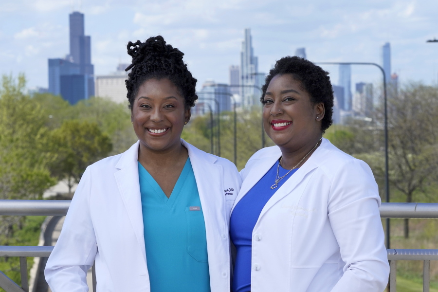 Dr. Brittani James, left, and her twin sister Dr. Brandi Jackson stand for a portrait in the Bronzeville neighborhood of Chicago, Sunday, May 2, 2021. The identical twin doctors who have fought bigotry all their lives have a lofty new mission: dismantling racism in medicine.