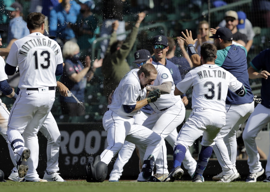 Seattle Mariners players surround Tom Murphy, center, after he hit a sacrifice fly, scoring the winning run, in the 10th inning against the Oakland Athletics on Monday in Seattle. The Mariners won their fifth straight game and improved to 5-0 in extra innings.