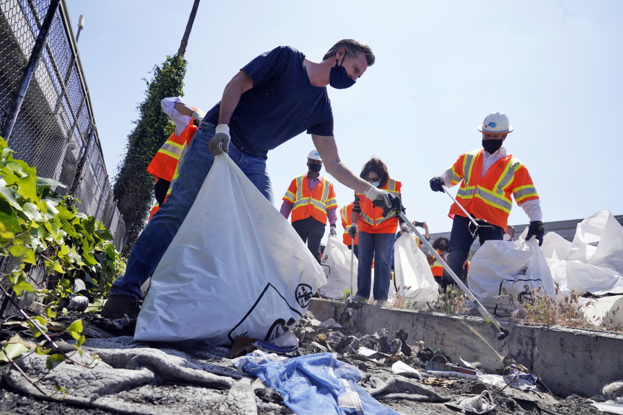 FILE - In this Tuesday, May 11, 2021, file photo, California Gov. Gavin Newsom joins a cleanup effort in Los Angeles. Newsom on Tuesday proposed $12 billion in new funding to get more people experiencing homelessness in the state into housing and to "functionally end family homelessness" within five years. A fading coronavirus crisis and an astounding windfall of tax dollars have reshuffled California's emerging recall election, allowing Democratic Gov. Newsom to talk of a mask-free future and propose billions in new spending for schools and businesses as he looks to fend off Republicans who depict him as a foppish failure.