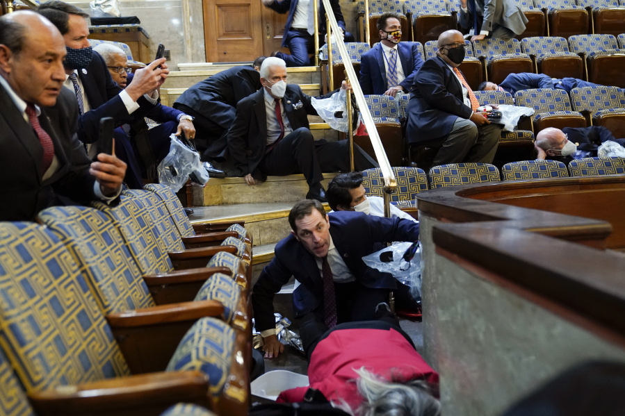 FILE - In this Jan. 6, 2021, file photo, people shelter in the House chamber as rioters try to break into the House Chamber at the U.S. Capitol in Washington.