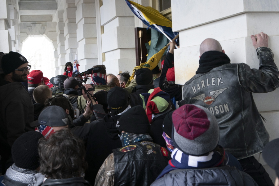 FILE - In this Jan. 6, 2021 file photo insurrectionists loyal to President Donald Trump try to open a door of the U.S. Capitol as they riot in Washington. At least a dozen of the 400 people charged so far in the Jan. 6 insurrection have made dubious claims about their encounters with officers at the Capitol. The most frequent argument is that they can't be guilty of anything, because police stood by and welcomed them inside, even though the mob pushed past police barriers, sprayed chemical irritants and smashed windows as chaos enveloped the government complex.