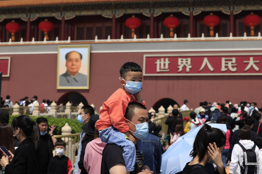 A man and child wearing masks visit Tiananmen Gate near the portrait of Mao Zedong in Beijing on May 3, 2021. China's population growth is falling closer to zero as fewer couples have children, the government announced Tuesday, May 11, 2021, adding to strains on an aging society with a shrinking workforce.