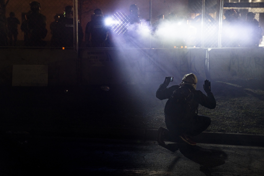 FILE- In this April 14, 2021, file photo,  police shine lights on a demonstrator with raised hands during a protest outside the Brooklyn Center Police Department on in Brooklyn Center, Minn., over the fatal shooting of Daunte Wright. Brooklyn Center, the Minneapolis suburb where a white police officer fatally shot Wright, a Black motorist in April, sparking a week of protests, planned a weekend vote on a resolution calling for major changes to its policing. The resolution backed by Brooklyn Center Mayor Mike Elliott would create a new division of unarmed civilian employees to handle traffic violations and another unarmed division to respond to people in crisis.