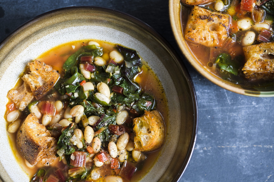 This image released by Milk Street shows a recipe for Tuscan Soup. Milk Street kitchens start from scratch with ciabatta croutons and canned white beans. Sturdy greens such as red-veined Swiss chard add color and texture from crispy stems. They are saut'eed with onions and bell pepper. If you like, serve the soup topped with grated Parmesan cheese.