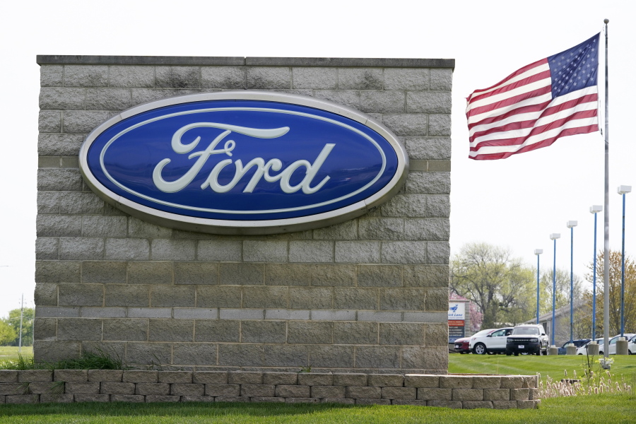 FILE - In this April 27, 2021 file photo, an American flag flies over a Ford auto dealership, in Waukee, Iowa. Ford says it expects 40% of its global sales to be battery-electric vehicles by 2030 as it adds billions to the amount its spending to develop them. Ahead of a presentation to Wall Street on Wednesday morning, May 26 the automaker says it will add about $8 billion to its EV development spending from this year to 2025.