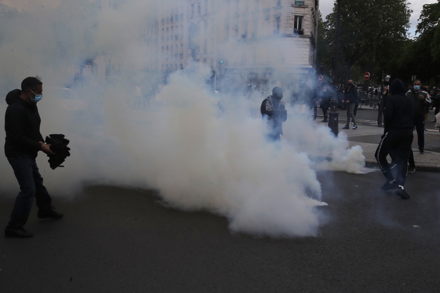 Demonstrators walk through tear gas grenades fired by police forces during a banned protest in support of Palestinians in the Gaza Strip, Saturday, May, 15, 2021 in Paris. Marches in support of Palestinians in the Gaza Strip were being held Saturday in a dozen French cities, but the focus was on Paris, where riot police got ready as organizers said they would defy a ban on the protest.