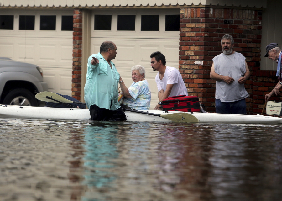 FILE - In this Aug. 27, 2017 file photo, people walk through floodwaters in Houston, Texas. The remnants of Hurricane Harvey sent devastating floods pouring into Houston. Houston area officials expressed shock and anger on Friday, May 21, 2021, after learning that their communities, which suffered the brunt of damage from Hurricane Harvey, would be getting a fraction of $1 billion that Texas is awarding as part of an initial distribution of federal funding given to the state for flood mitigation.