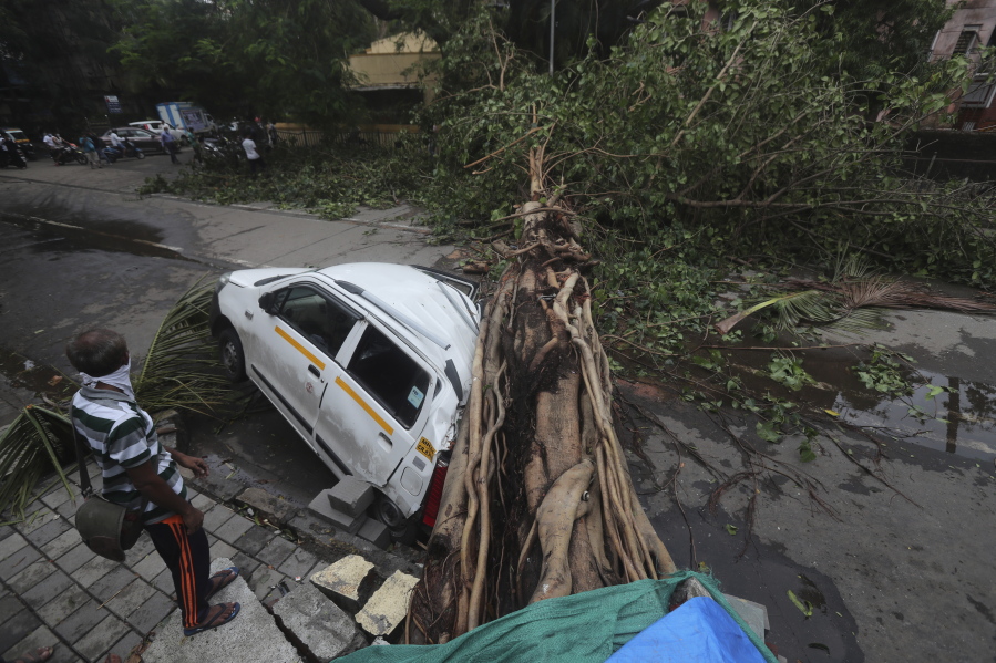 A car stands damaged with a fallen tree after heavy rainfall in Mumbai India, Tuesday, May 18, 2021. The Maharashtra state capital was largely spared from any major damage as Cyclone Tauktae, the most powerful storm to hit the region in more than two decades, came ashore in neighboring Gujarat state late Monday.
