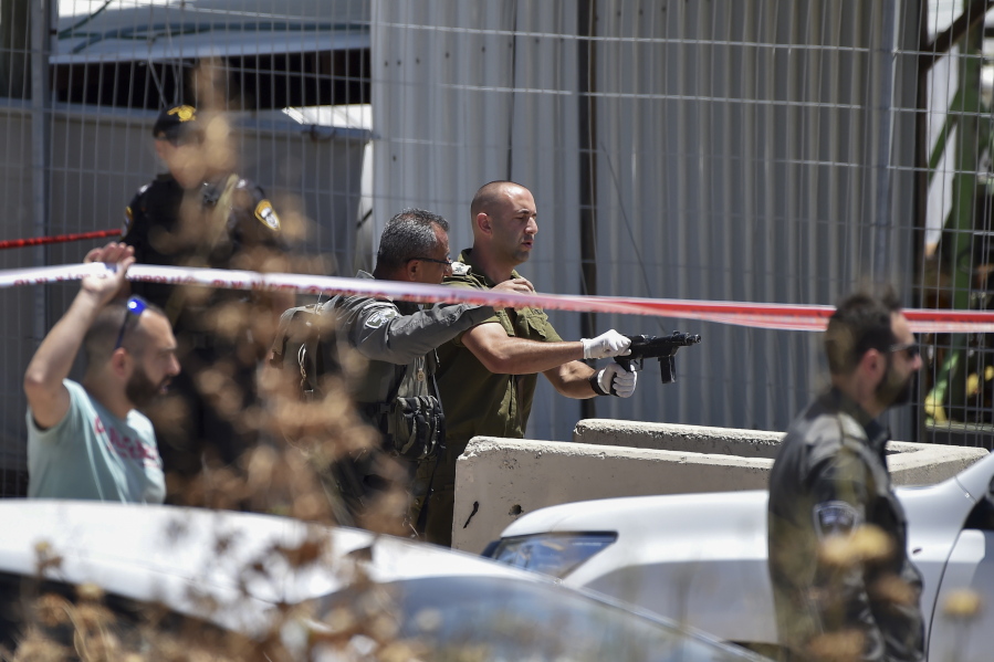 An IDF officer inspects the weapon used by a Palestinian gunmen at the scene of shooting attack in front of the military base of Salem near the West Bank town of Jenin, Friday, May. 7, 2021. Israeli troops shot and killed two Palestinians and wounded a third after the men opened fire on a Border Police base in the occupied West Bank. It was the latest in a series of violent confrontations amid soaring tensions in Jerusalem.
