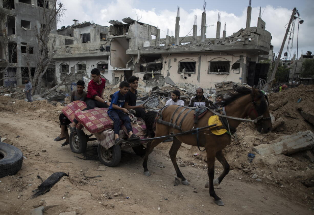 Palestinians on a horse carte loaded with belongings, pass by destroyed homes, to which they returned following a cease-fire reached after an 11-day war between Gaza's Hamas rulers and Israel, in town of Beit Hanoun, northern Gaza Strip, Friday, May 21, 2021.