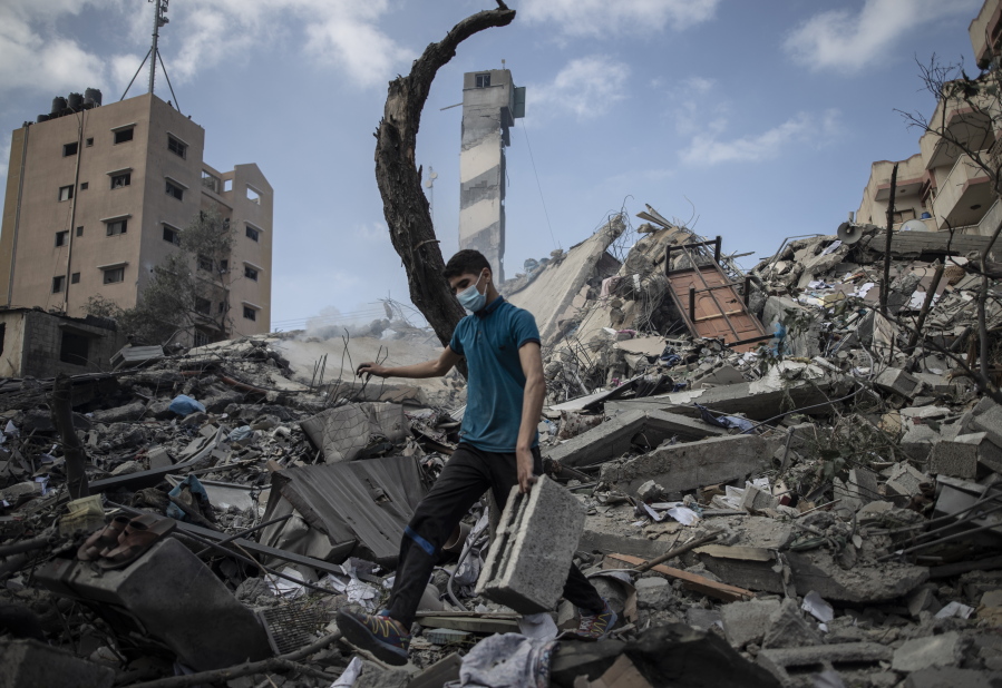 A Palestinian man inspects the damage of a six-story building which was destroyed by an early morning Israeli airstrike, in Gaza City, Tuesday, May 18, 2021. Israel carried out a wave of airstrikes on what it said were militant targets in Gaza, leveling a six-story building in downtown Gaza City, and Palestinian militants fired dozens of rockets into Israel early Tuesday, the latest in the fourth war between the two sides, now in its second week.