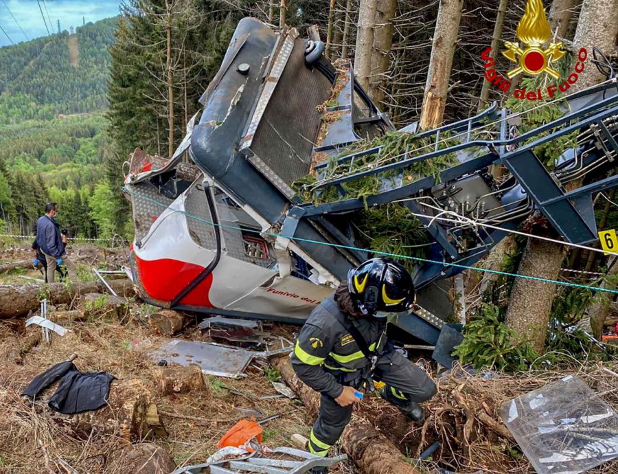 Rescuers work by the wreckage of a cable car after it collapsed near the summit of the Stresa-Mottarone line in the Piedmont region, northern Italy, Sunday, May 23, 2021. A cable car taking visitors to a mountaintop view of some of northern Italy's most picturesque lakes plummeted to the ground Sunday and then tumbled down the slope, killing at least 13 people and sending two children to the hospital, authorities said.
