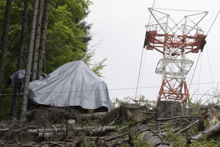 The wreckage of a cable car after it collapsed near the summit of the Stresa-Mottarone line in the Piedmont region, northern Italy, Wednesday, May 26, 2021. Police have made three arrests in the cable car disaster that killed 14 people after an investigation showed a clamp, placed on the brake as a patchwork repair effort, prevented the brake from engaging after the lead cable snapped.