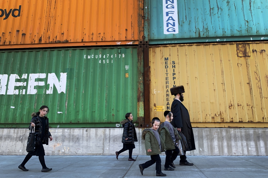 Members of the Orthodox Jewish community walk past shipping containers in the South Williamsburg neighborhood of Brooklyn, New York, in March.