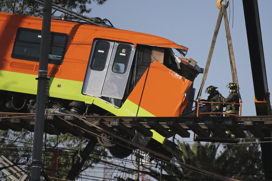 Firefighters work to lower to the ground a subway car dangling from a collapsed elevated section of the metro, in Mexico City, Tuesday, May 4, 2021. The elevated section of Mexico City's metro collapsed late Monday killing at least 23 people and injuring at least 79, city officials said.