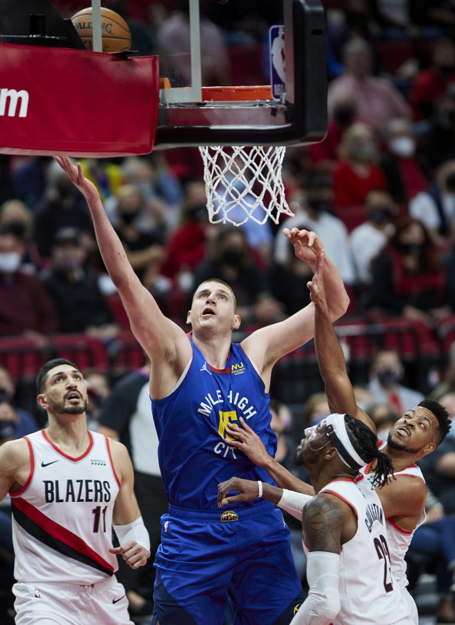 Denver Nuggets center Nikola Jokic, center, shoots over Portland Trail Blazers guard CJ McCollum, right, forward Robert Covington, second from right, and center Enes Kanter, left, during the first half of Game 3 of an NBA basketball first-round playoff series Thursday, May 27, 2021, in Portland, Ore.