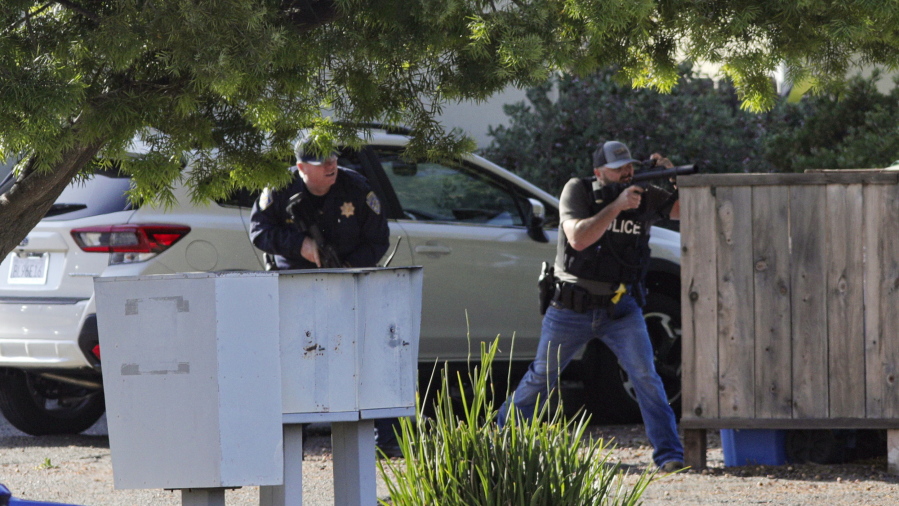 Officers take aim at an apartment across Camilla Court, Monday, May 10, 2021, in San Luis Obispo, Calif. Police said two police officers have been shot while serving a search warrant and the suspect has died.
