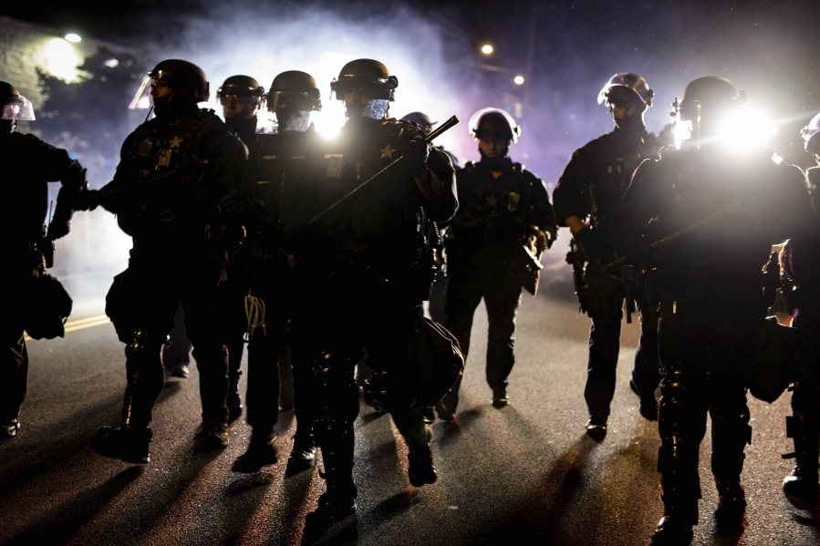 In this Aug. 9, 2020 photo, Portland, Ore., police officers in riot gear advance on a group of protesters after a demonstration was declared an "unlawful assembly." Despite passage of a 2020 Oregon law tracking decertified officers statewide, most complaints of misconduct remain closed.