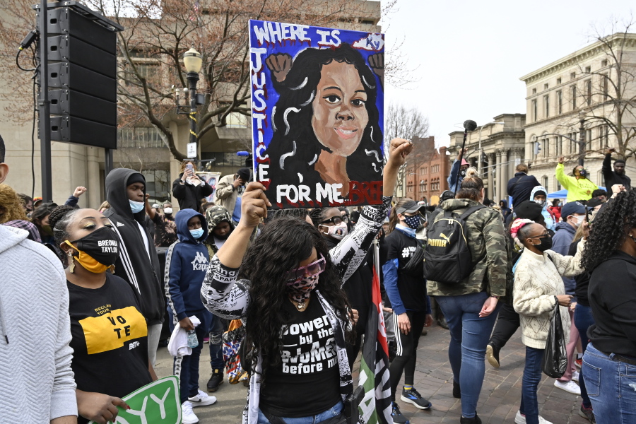 FILE - In this March 13, 2021 file photo, a protester holds up a painting of Breonna Taylor during a rally on the one year anniversary of her death at Jefferson Square Park in Louisville, Ky.   On Friday, April 9, 2021, Gov. Andy Beshear has signed a partial ban on no-knock warrants a year after the fatal shooting of Taylor.  (AP Photo/Timothy D.