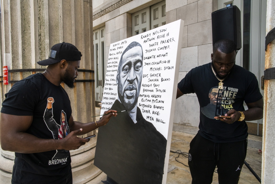 Artist Dennis Owes, 31, from Ghana gives the last touch to his portrait of George Floyd during a rally on Sunday in the Brooklyn borough of New York.