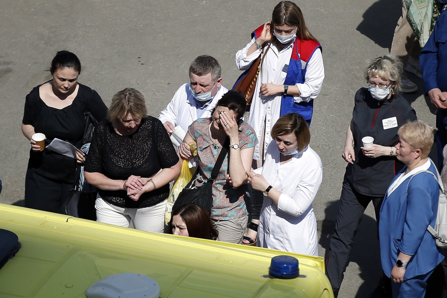 Medics and friends help a woman board an ambulance at a school after a shooting in Kazan, Russia, Tuesday, May 11, 2021. Russian media report that several people have been killed and four wounded in a school shooting in the city of Kazan. Russia's state RIA Novosti news agency reported the shooting took place Tuesday morning, citing emergency services.