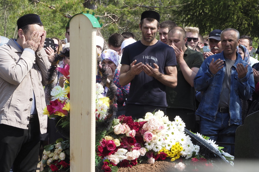 People pray Wednesday next to the grave of Elvira Ignatyeva, an English language teacher who was killed in the shooting at School No. 175 in Kazan, Russia.