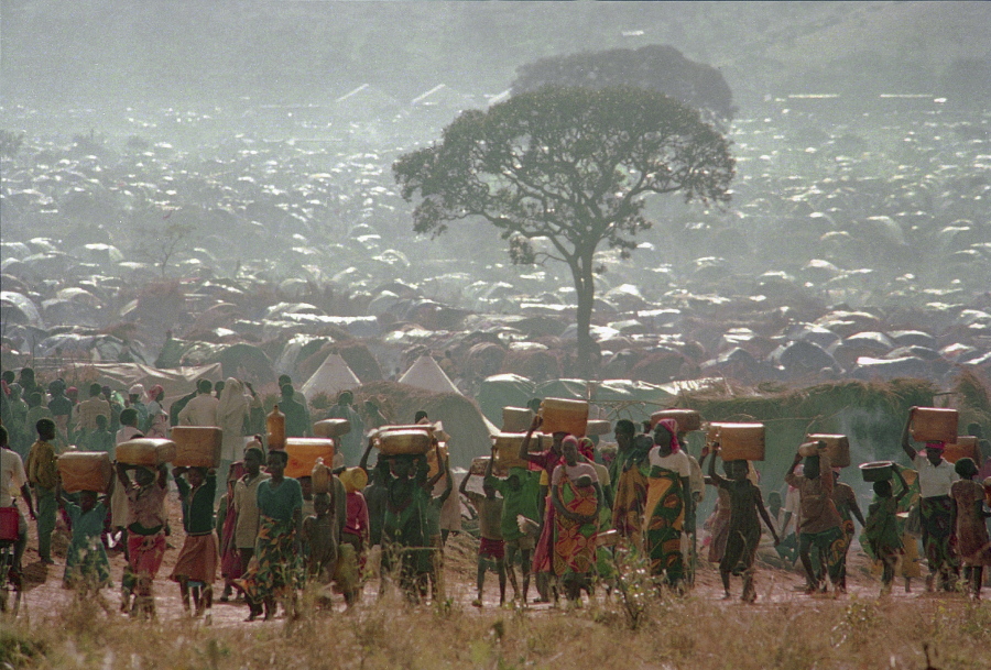 FILE - In this Tuesday, May 17, 1994 file photo, refugees who fled the ethnic bloodbath in neighboring Rwanda carry water containers back to their huts at the Benaco refugee camp in Tanzania, near the border with Rwanda. A report commissioned by the Rwandan government due to be made public on Monday, April 19, 2021 concludes that the French government bears "significant" responsibility for "enabling a foreseeable genocide" that left more than 800,000 dead in 1994 and that that France "did nothing to stop" the massacres.
