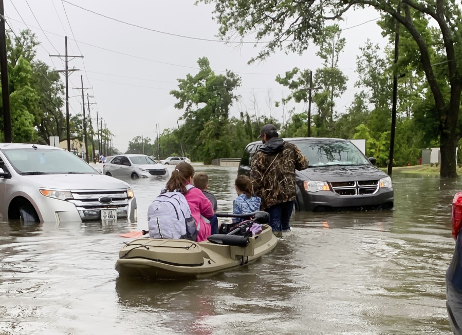 Parents use boats to pick up students from schools after nearly a foot of rain fell in Lake Charles, La., Monday, May 17, 2021.