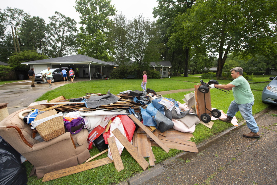 Homeowner Stephen Punkay, right, dumps a cart-load of wet carpet to add to the debris pile, after the Baker Drive home that he and wife Amy share with their six children got at least six inches of water in Monday night's deluge of rain in the Westminster subdivision, as they clean up with the help of family, neighbors and "church family" from Community Bible Church, on Tuesday, May 18, 2021, in Baton Rouge, La. Heavy rains have swept across southern Louisiana, flooding homes, swamping cars and closing a major interstate.