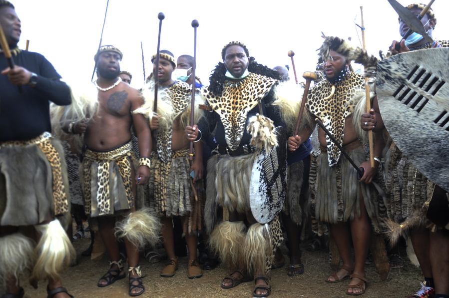 Prince Misuzulu Zulu, centre, flanked by fellow warriors in traditional dress at the KwaKhangelamankengane Royal Palace, during a ceremony, in Nongoma, Friday May 7, 2021. A new Zulu king in South Africa has been named amid scenes of chaos as other members of the royal family questioned Prince Misuzulu Zulu's claim to the title. He was suddenly whisked away from the public announcement at a palace by bodyguards. The controversy over the next king has arisen after the death in March of King Goodwill Zwelithini, who had reigned since 1968. Zwelithini apparently named one of his six wives, Queen Mantfombi Shiyiwe Dlamini Zulu, as the "regent of the Zulu kingdom" in his will. But her death just over a week ago after holding the title for only a month has thrown the royal succession into turmoil.