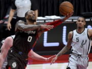 Portland Trail Blazers guard Damian Lillard, left, shoots as San Antonio Spurs guard Dejounte Murray, right, watches during the second half of an NBA basketball game in Portland, Ore., Saturday, May 8, 2021.