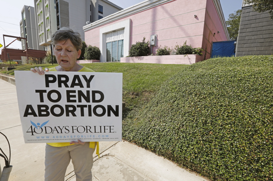 FILE - In this Oct. 2, 2019. file photo, an abortion opponent sings to herself outside the Jackson Womens Health Organization clinic in Jackson, Miss. The Supreme Court has agreed to hear a potentially ground-breaking abortion case, and the news is energizing activists on both sides of the contentious issue. They're already girding to make abortion access a high-profile issue in next year's midterm elections. (AP Photo/Rogelio V.