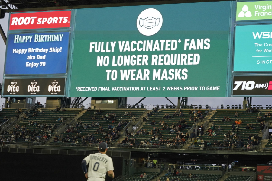 Fans sit in a special section for people who are fully vaccinated against COVID-19, at T-Mobile Park during a baseball game between the Seattle Mariners and the Detroit Tigers, Monday, May 17, 2021, in Seattle. Monday was the first day that fans fully vaccinated against COVID-19 were not required to wear masks at the ballpark, as shown on the video display. (AP Photo/Ted S.
