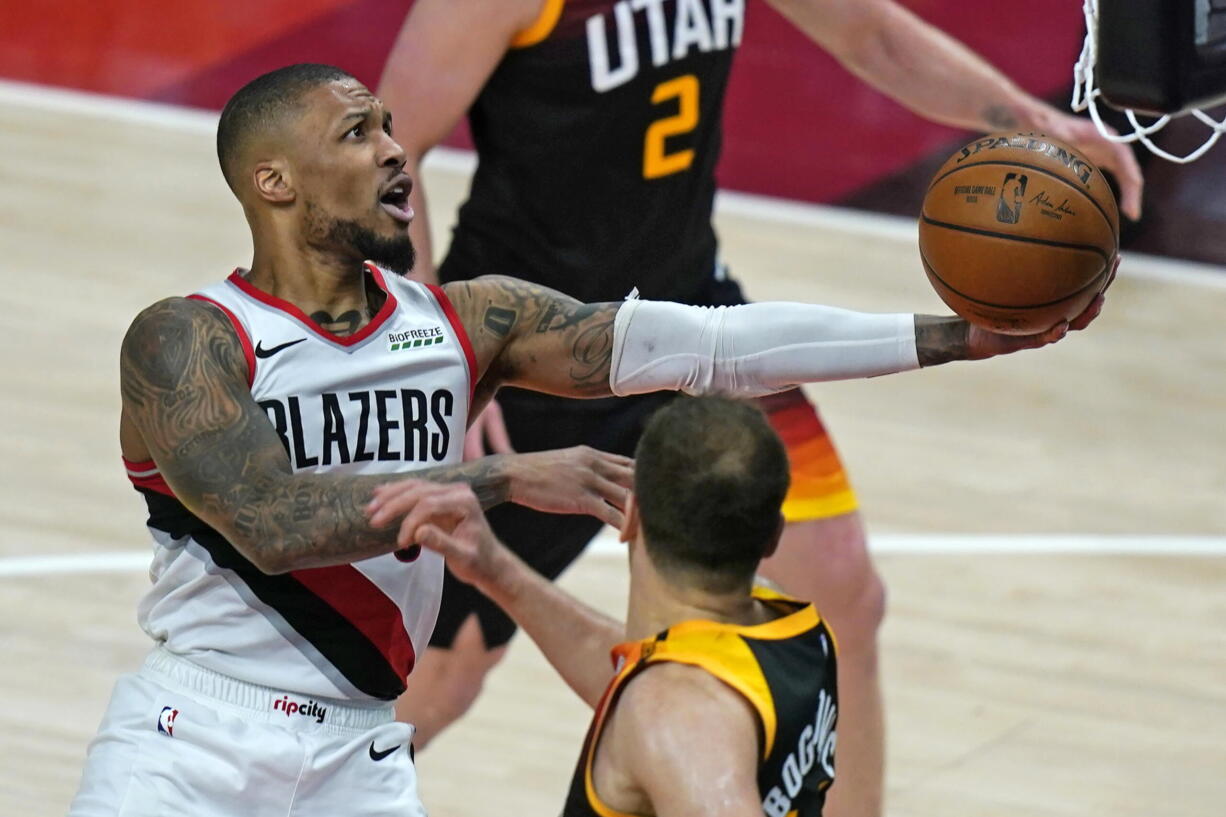 Portland Trail Blazers guard Damian Lillard, left, lays the ball up as Utah Jazz forward Bojan Bogdanovic, right, watches during the second half of an NBA basketball game Wednesday, May 12, 2021, in Salt Lake City.
