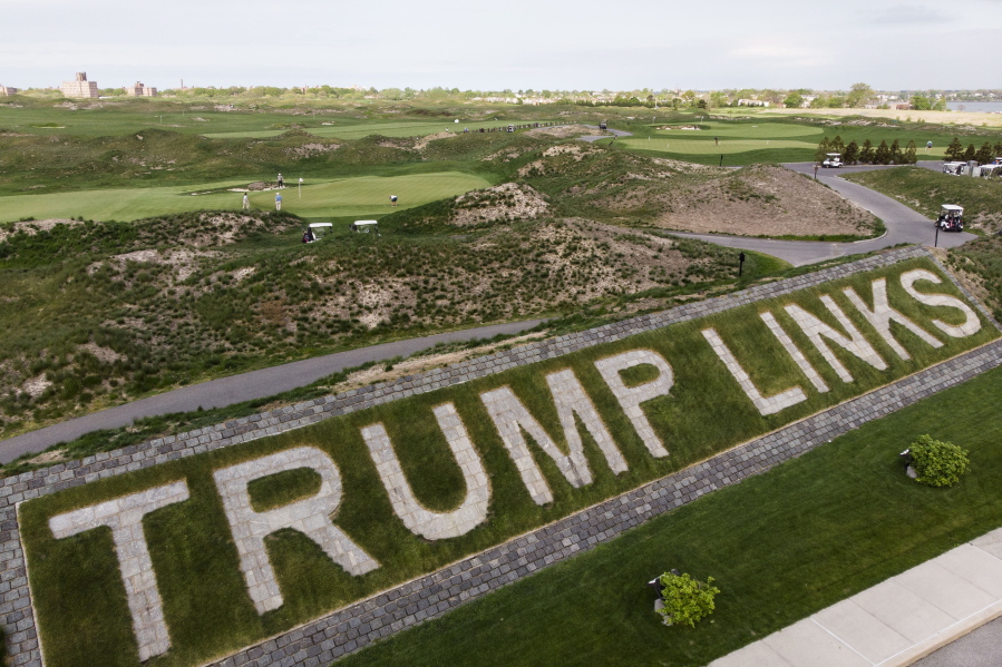 Patrons play the links as a giant branding sign is displayed with flagstones at Trump Golf Links at Ferry Point in the Bronx borough of New York on Tuesday, May 4, 2021. Former President Donald Trump has a rich history of fighting back when he's down and making others pay, and that's exactly how he intends to deal with New York City over its plans to fire his company from running the city golf course.