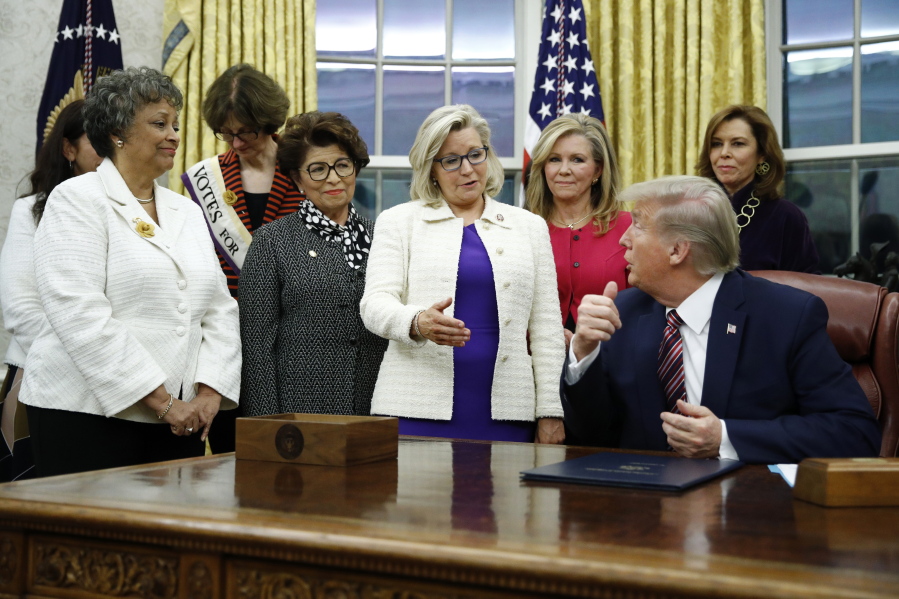 FILE - In this Nov. 25, 2019, file photo, Rep. Liz Cheney, R-Wyo., center, speaks with President Donald Trump during a bill signing ceremony for the Women's Suffrage Centennial Commemorative Coin Act in the Oval Office of the White House in Washington.