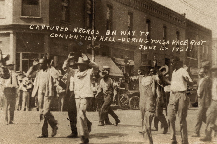 In this photo provided by the Department of Special Collections, McFarlin Library, The University of Tulsa, a group of Black men are marched past the corner of 2nd and Main Streets in Tulsa, Okla., under armed guard during the Tulsa Race Massacre on June 1, 1921. On May 31, 1921, carloads of Black residents, some of them armed, rushed to the sheriff's office downtown to confront whites who were gathering apparently to abduct and lynch a Black prisoner in the jail. Gunfire broke out, and over the next 24 hours, a white mob inflamed by rumors of a Black insurrection stormed the Greenwood district and burned it, destroying all 35 square blocks. Estimates of those killed ranged from 50 to 300.
