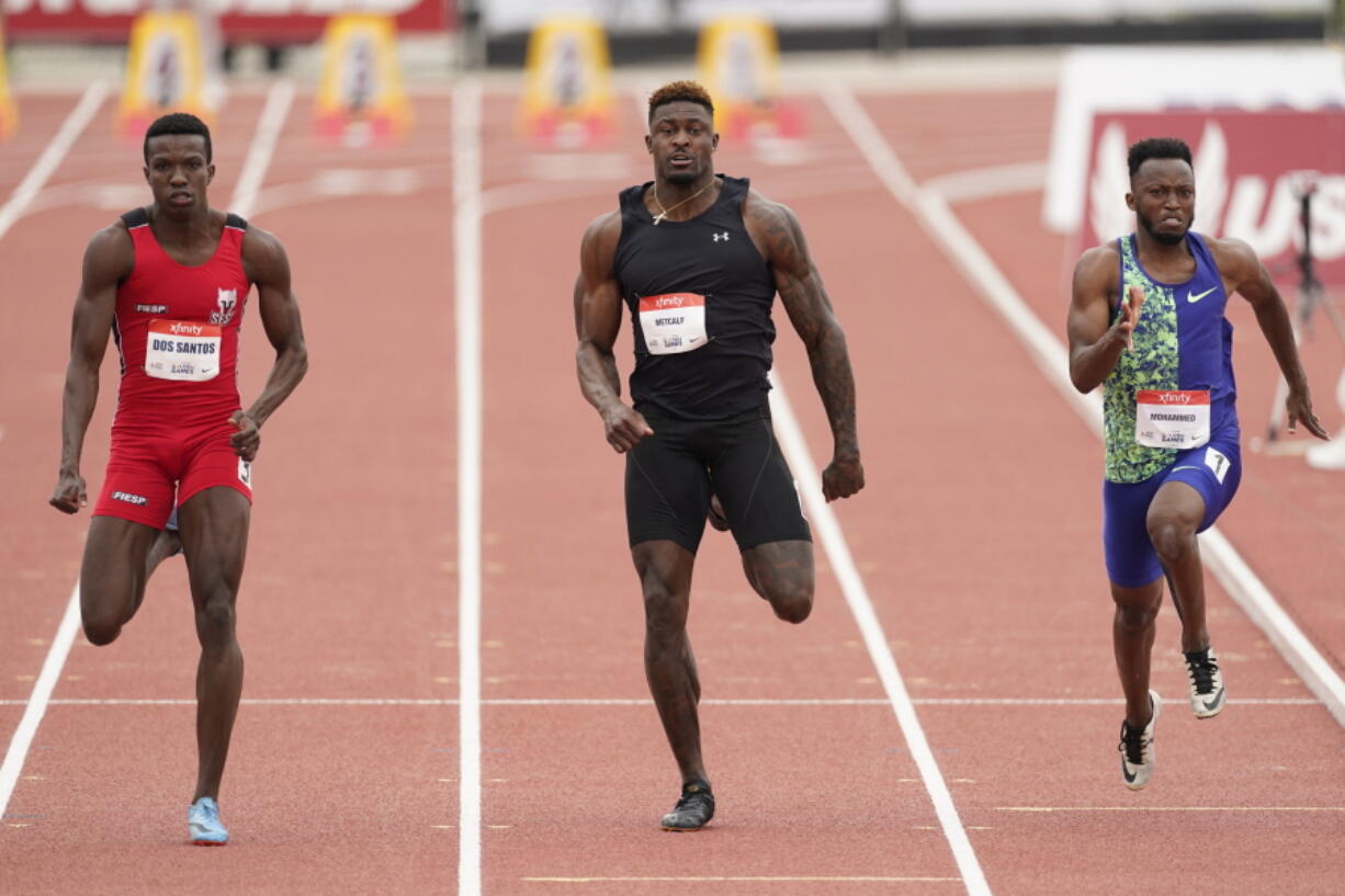 Seattle Seahawks wide receiver DK Metcalf, center, competes in the second heat of the men's 100-meter dash prelim during the USATF Golden Games at Mt. San Antonio College Sunday, May 9, 2021, in Walnut, Calif. At left is Felipe Bardi Dos Santos and at right is Abdullah Mohammed.
