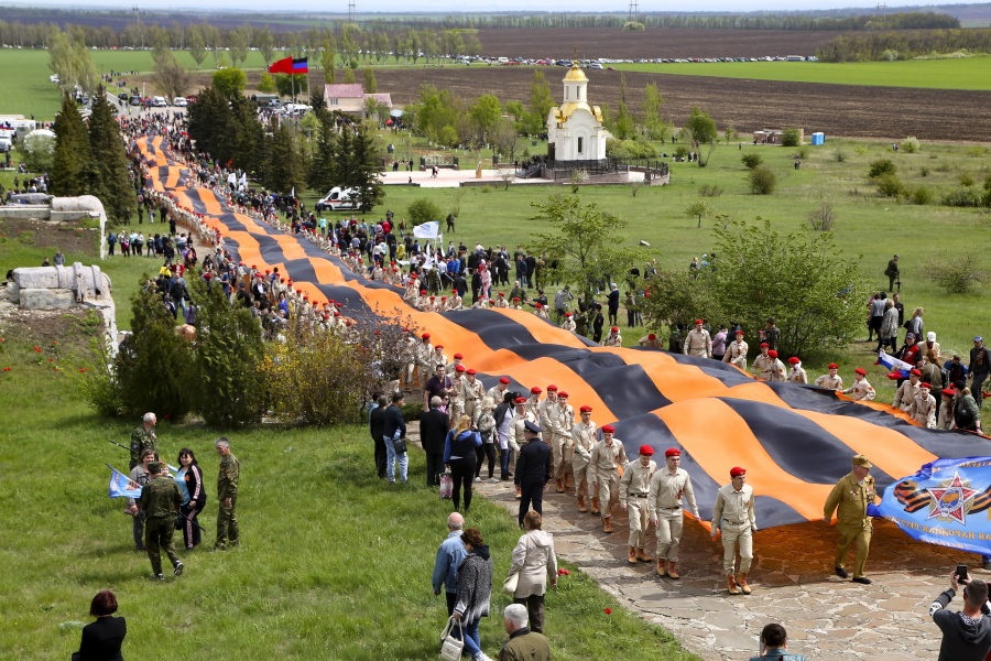 Activists carry a 300 meter long St. George ribbon, which has become a symbol of the pro-Russian insurgency in eastern Ukraine, during celebrations of the Victory Day at a World War II memorial in Saur-Mogila, about 60 km. (31 miles) east of Donetsk, eastern Ukraine, Saturday, May 8, 2021. Efforts have stalled to end the conflict between Russia-backed rebels and Ukrainian forces, which has killed more than 14,000 people since it broke out in 2014. Russia, which claims it has no military presence in eastern Ukraine, fueled the tensions this year by massing troops and conducting large-scale military exercises near its border with Ukraine.
