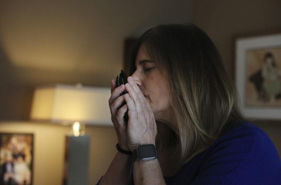Michelle Pepe tries to smell her late father's wallet while going through his belongings one year after he died of the coronavirus, in Sharon, Mass., on Wednesday, April 14, 2021. After contracting the virus herself, Pepe lost and has not regained her sense of smell. She keeps her father's belongings in hopes that one day it comes back and she can smell him again.