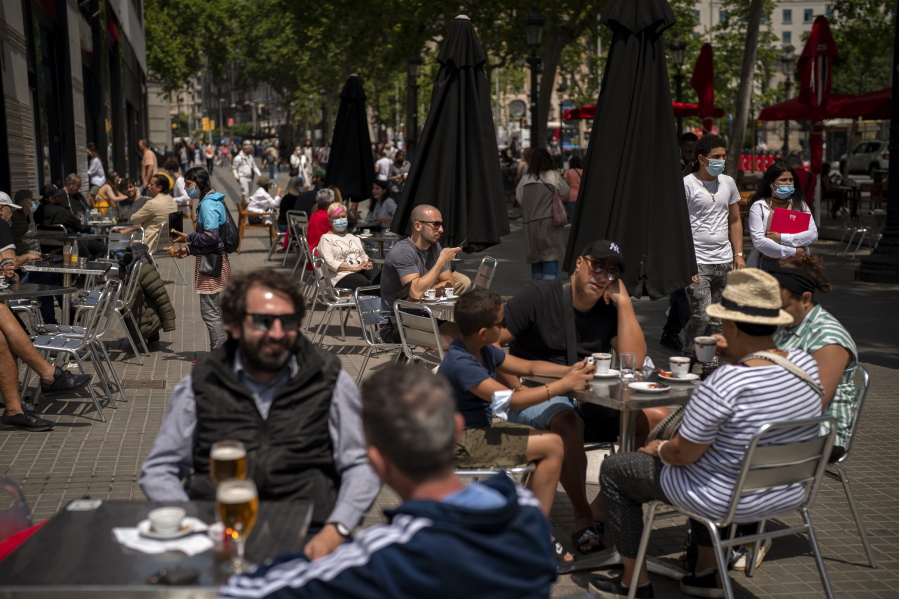FILE - In this May 28, 2021, file photo, customers sit in a terrace bar in downtown Barcelona, Spain. Coronavirus infections, hospitalizations and deaths are plummeting across much of Europe. Vaccination rates are accelerating, and with them, the promise of summer vacations.