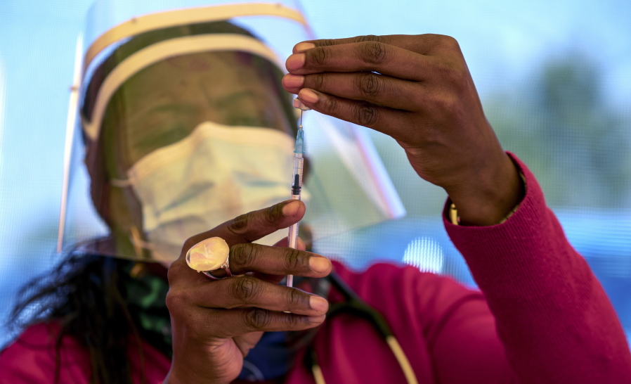 A health worker prepares a dose of the Pfizer coronavirus vaccine at the newly-opened mass vaccination program for the elderly at a drive-thru vaccination center outside Johannesburg, South Africa, Tuesday, May 25, 2021. South Africa aims to vaccinate 5 million of its older citizens by the end of June.