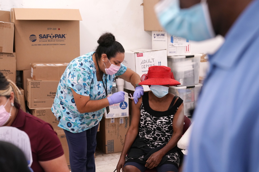 FILE - In this April 10, 2021, file photo, registered nurse Ashleigh Velasco, left, administers the Johnson & Johnson COVID-19 vaccine to Rosemene Lordeus, right, at a clinic held by Healthcare Network in Immokalee, Fla. Fewer Americans are reluctant to get a COVID-19 vaccine than just a few months ago, but questions about side effects and how the shots were tested still hold some back, according to a new poll that highlights the challenges at a pivotal moment in the U.S. vaccination campaign.